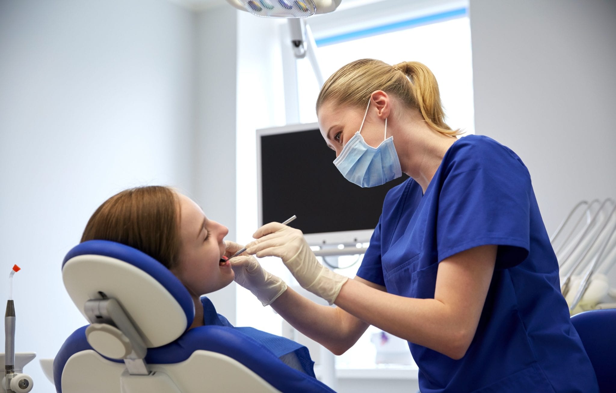 Female In Blue Scrubs Performing Dental Cleaning on Patient