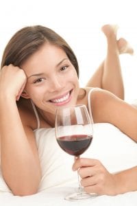Female Resting on Bed With Wine Glass