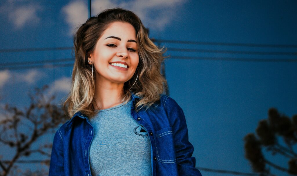 Portrait of a smiling young woman outdoors with a blue sky background.