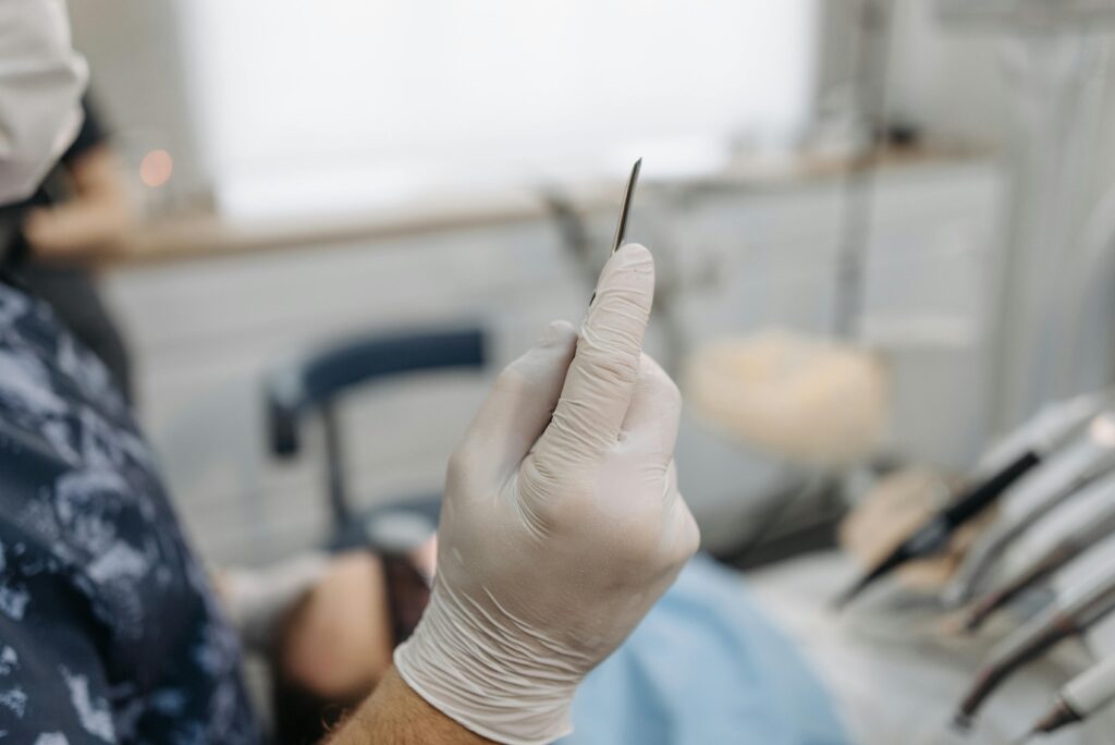 Dentist wearing gloves holds a precision tool in a dental clinic setting.