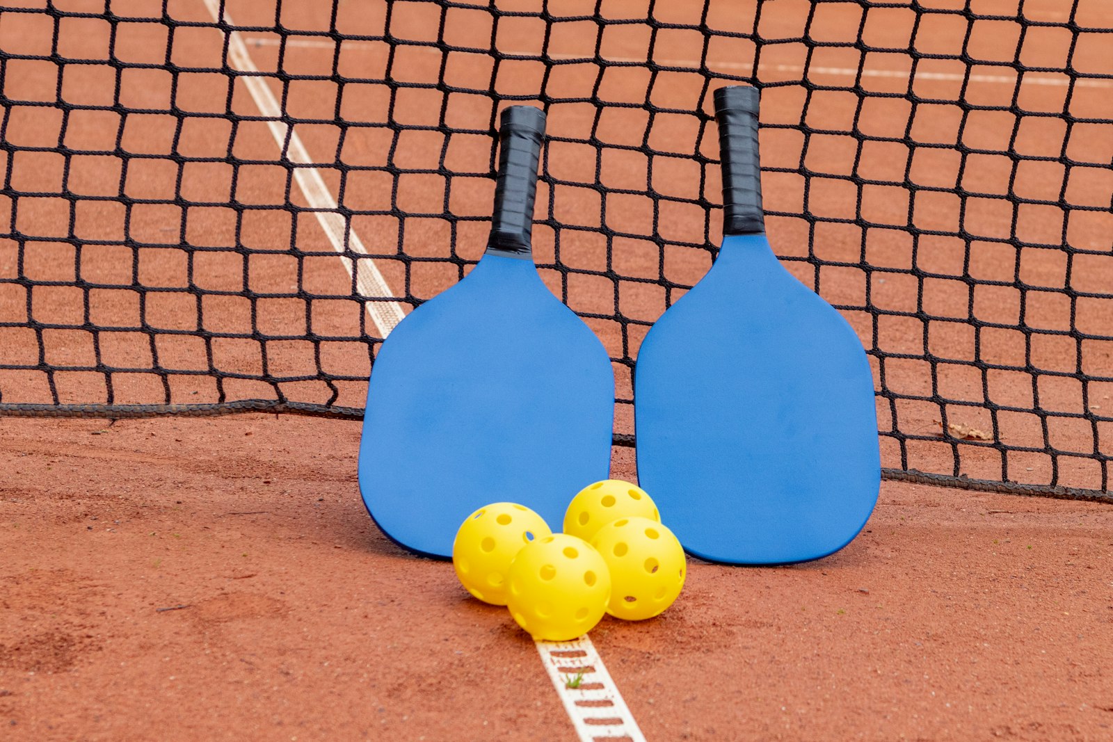 A pickleball paddle and ball on the court, a summer sport where a mouthguard can protect your teeth