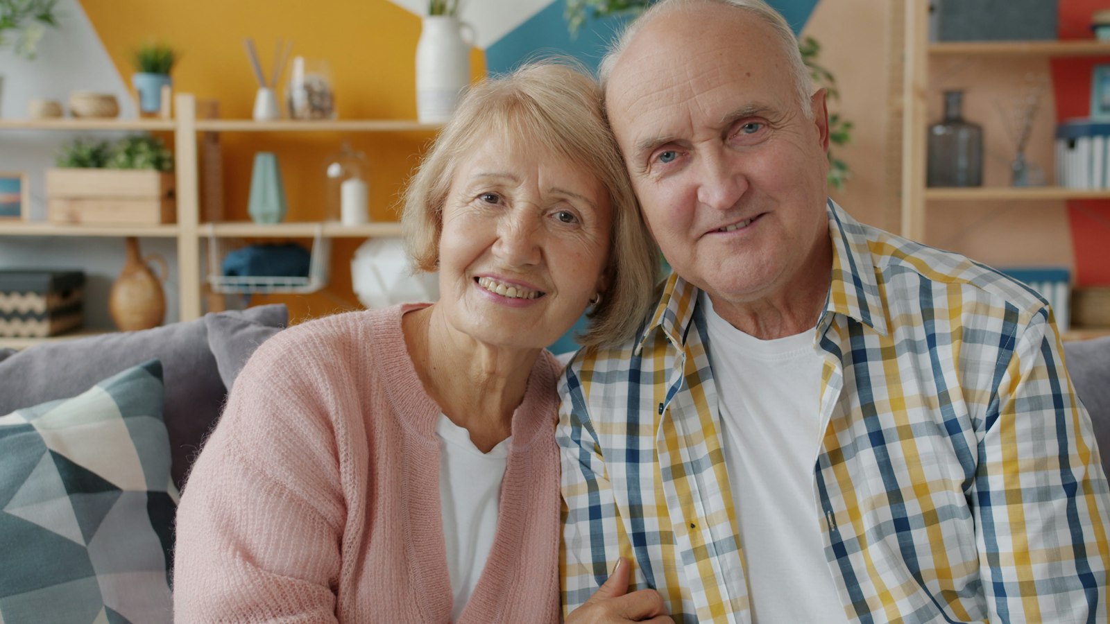 Older couple smiling confidently after full-arch tooth replacement in Belmont MA