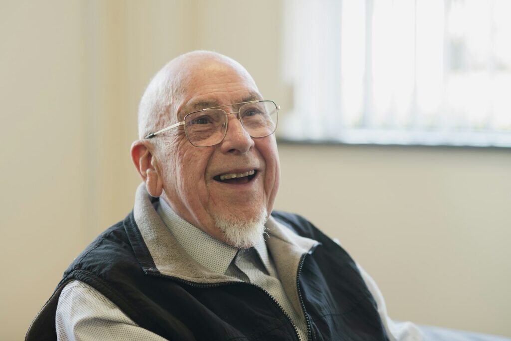 Older adult smiling confidently with snap-in implant-supported dentures in Belmont MA
